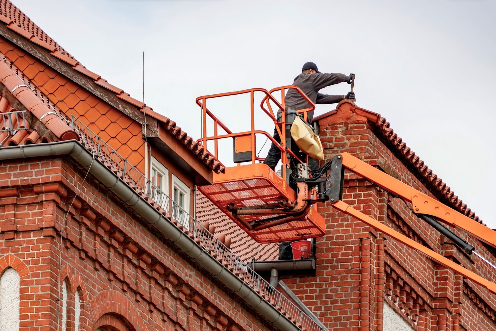 Roofer replacing ridge tiles from a cherry picker